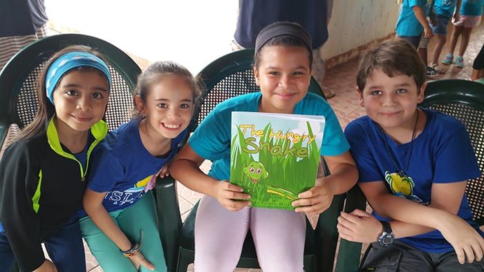Suzanne reading aloud to a class of children sitting on the floor.